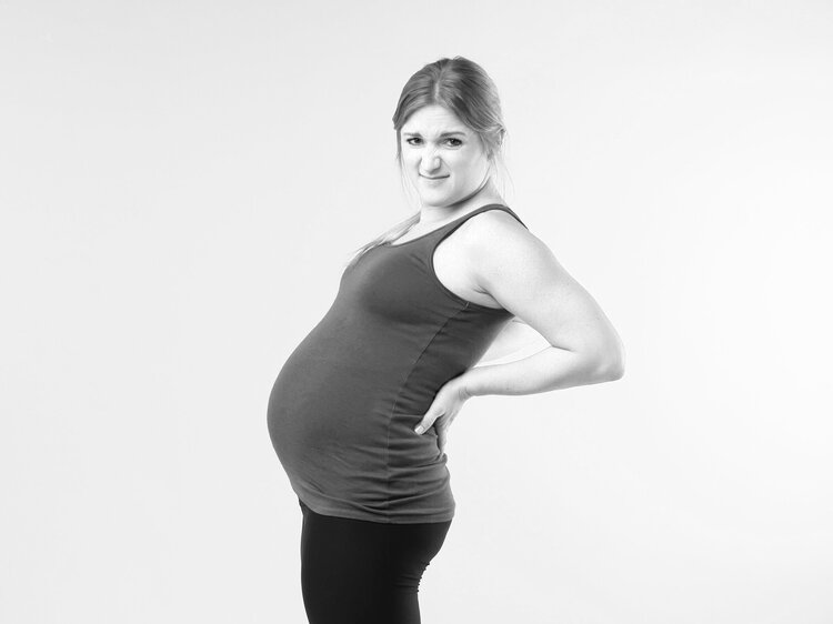 woman with pregnant belly stands leaning back to demonstrate incorrect posture