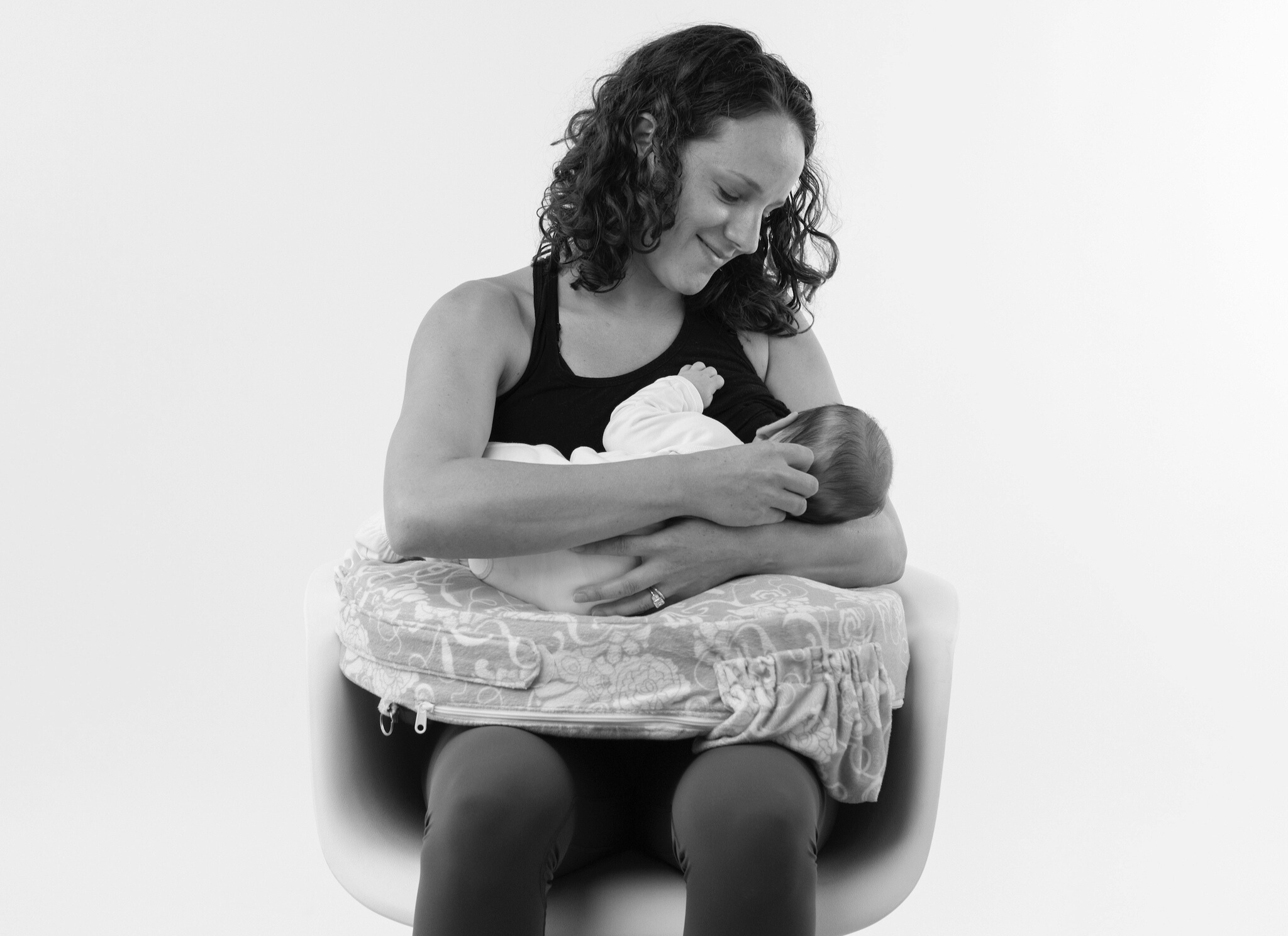 woman sitting in chair with pillow holding baby