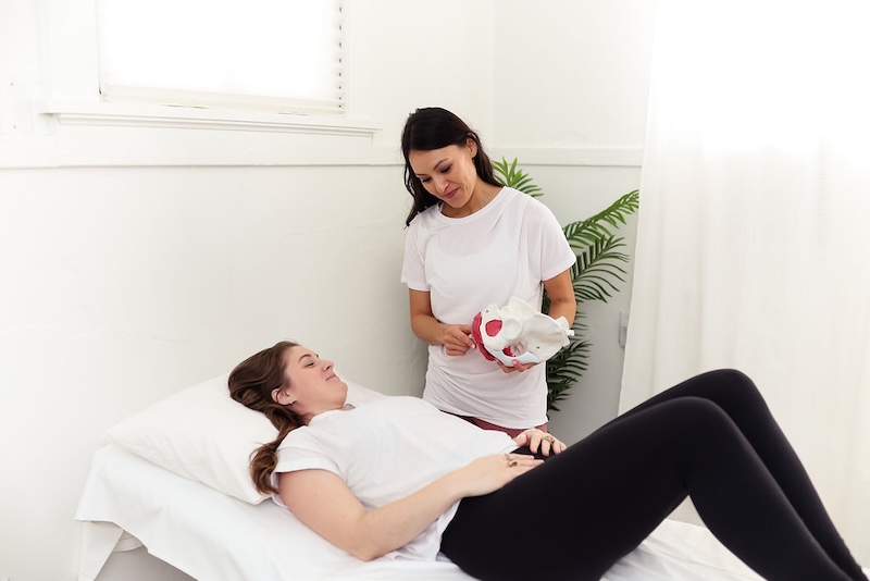 therapist demonstrating with a pelvic model to a patient