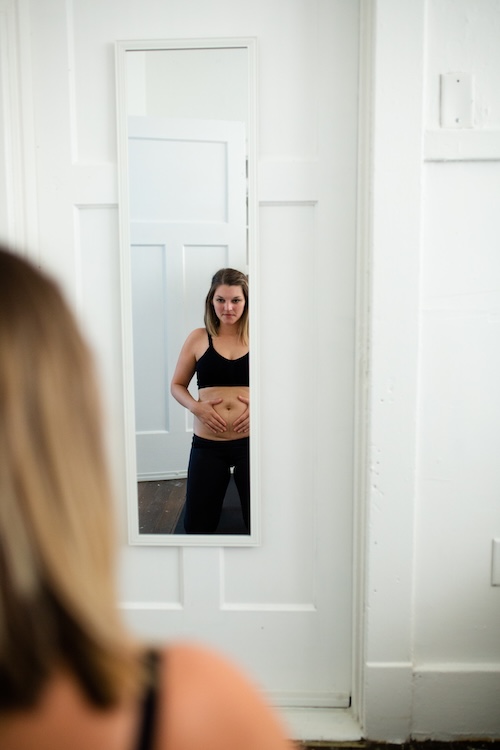 woman looking at herself in mirror postpartum