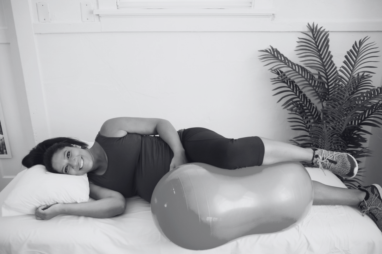 a pregnant woman lays on her side, a peanut ball between her legs