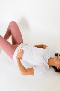 Woman lies on back with knees bent and hands resting on stomach.