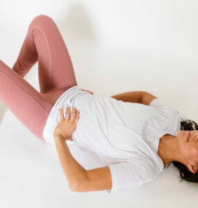 Woman lies on back with knees bent and hands resting on stomach.