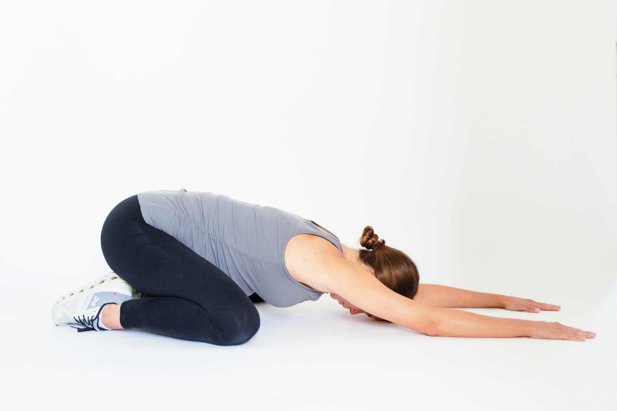 Pregnant woman leans back into child's pose.