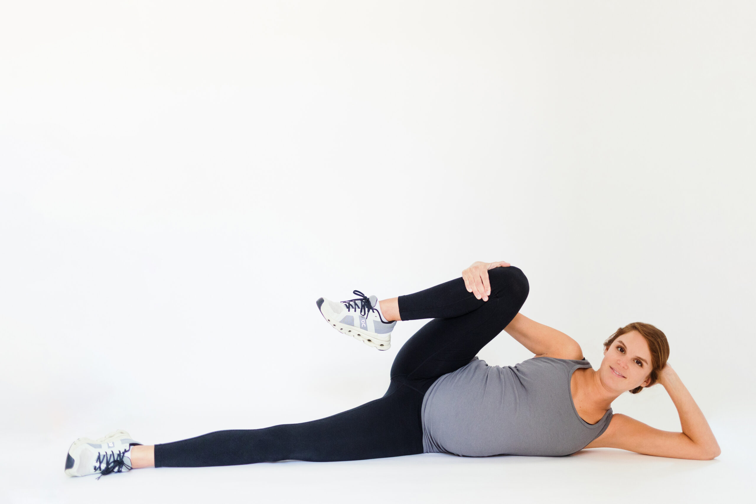 Pregnant woman lays on side, holding one knee up.