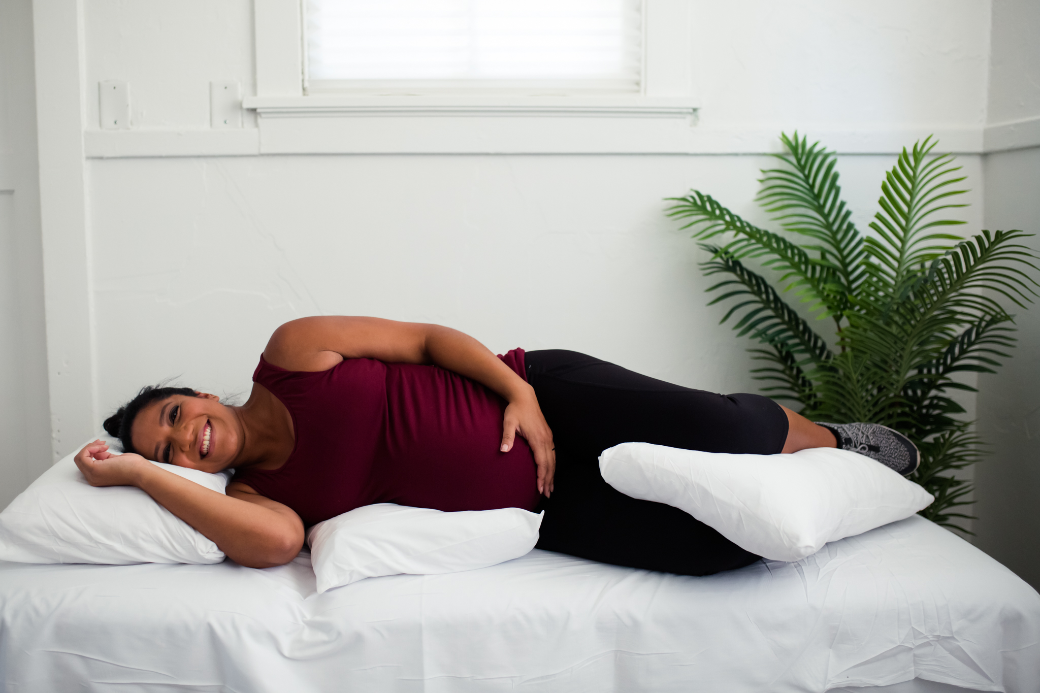 Pregnant woman lies on side with pillow supports