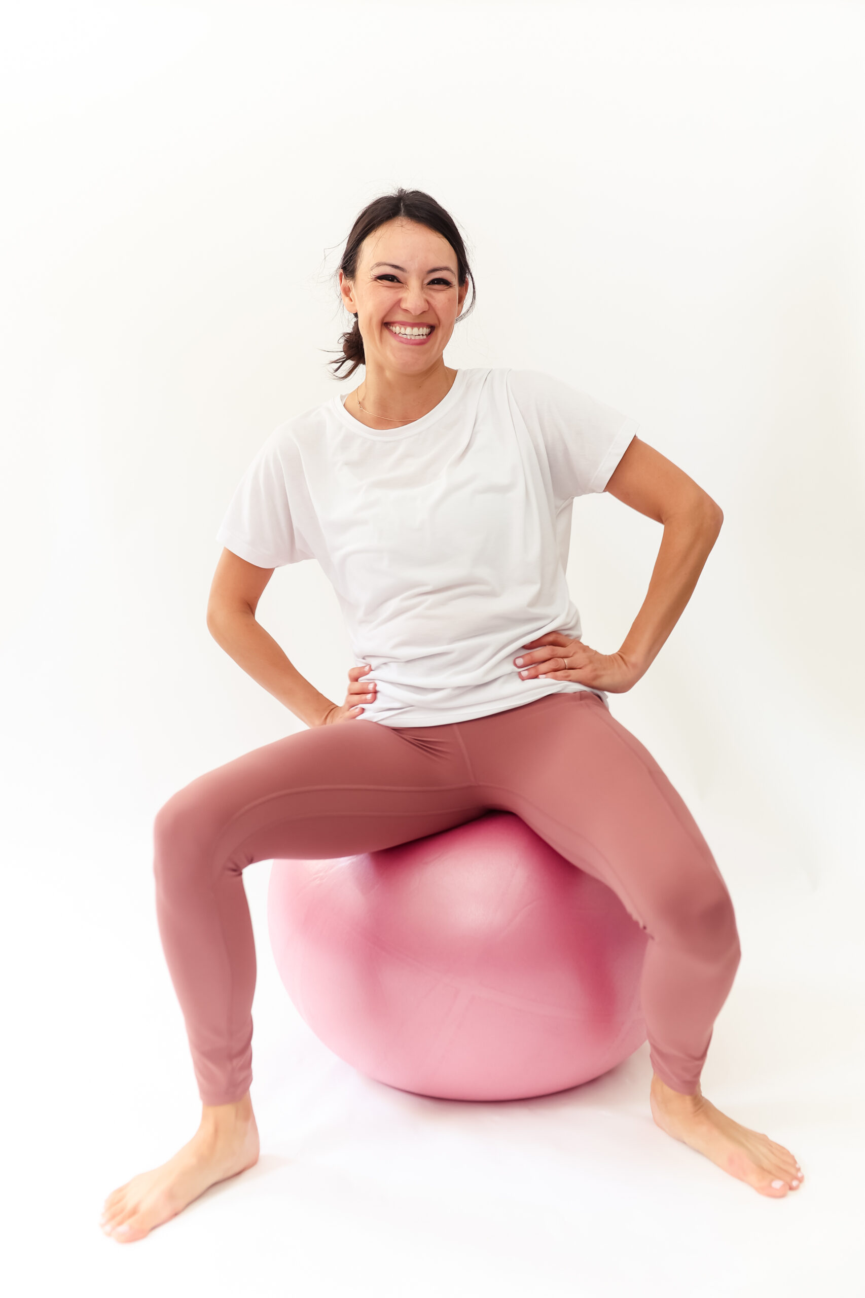 Woman sits on birth ball, smiling