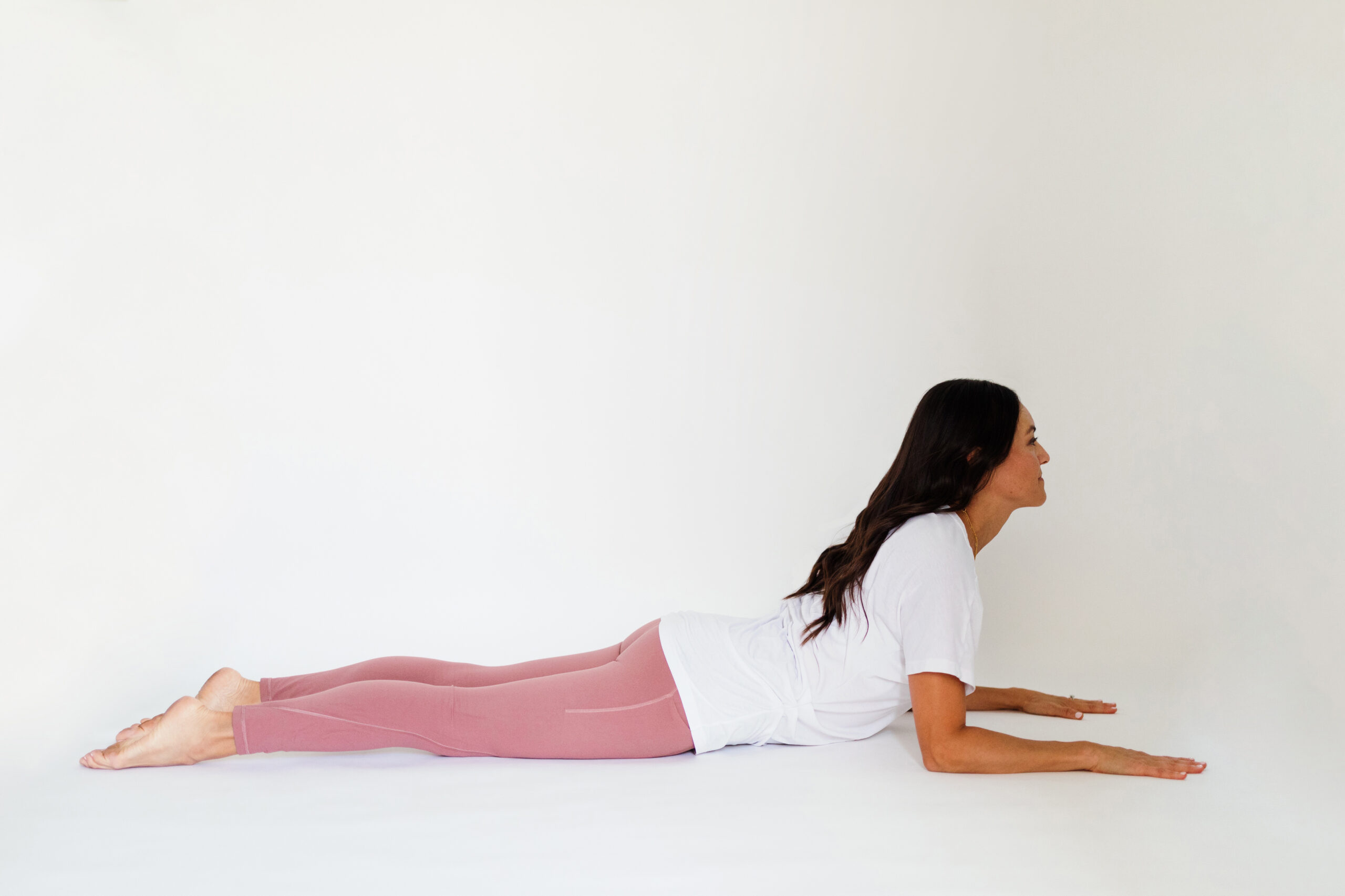 Woman lies on ground and pushes up on her elbows into cobra pose