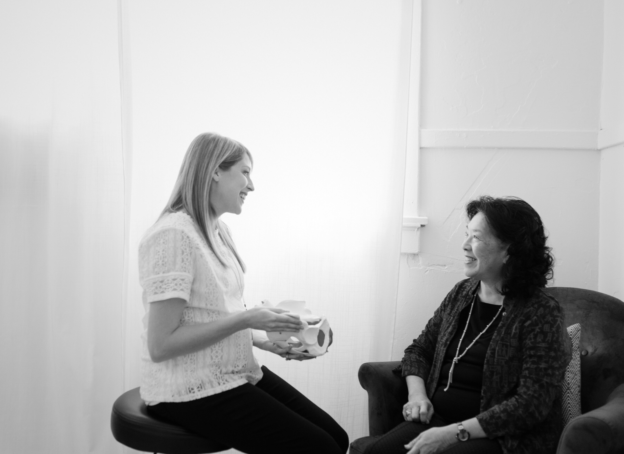 Client and therapist sit in an office, smiling.